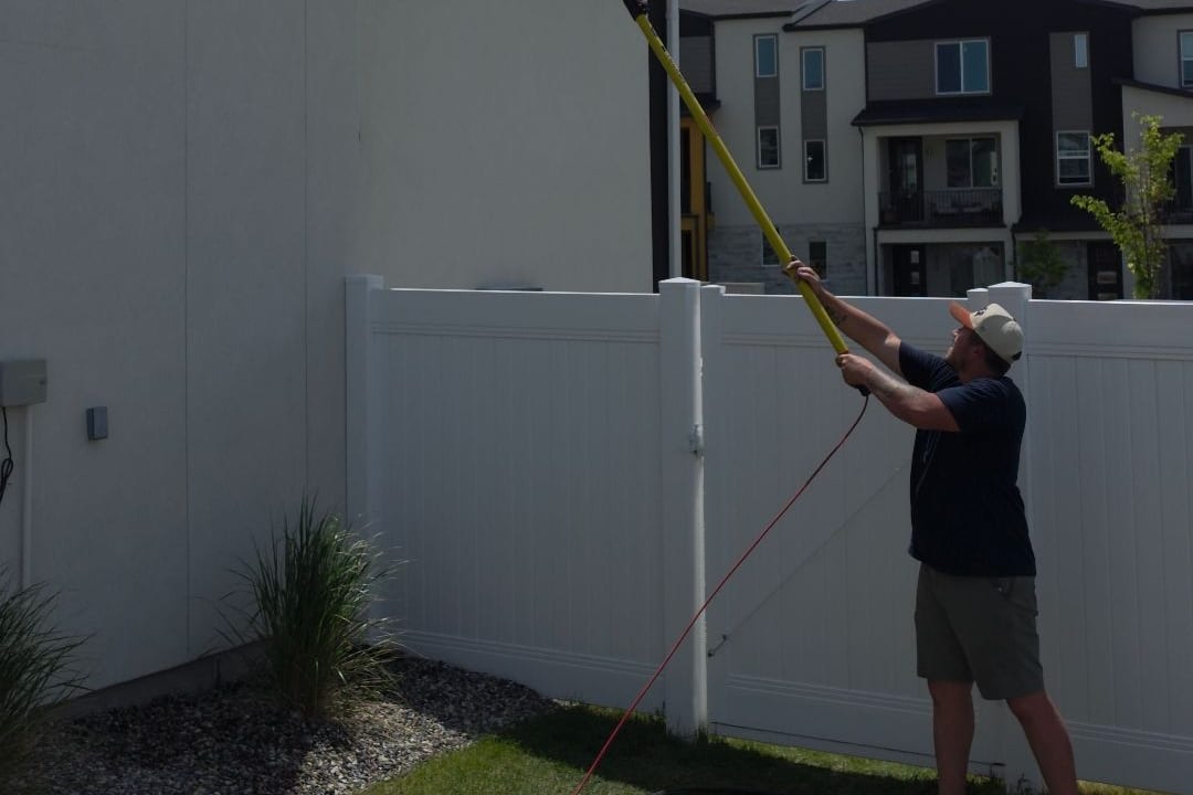 Exterior window cleaning in Taylorsville, Utah — Ember technician cleaning a second-story window with a water-fed pole