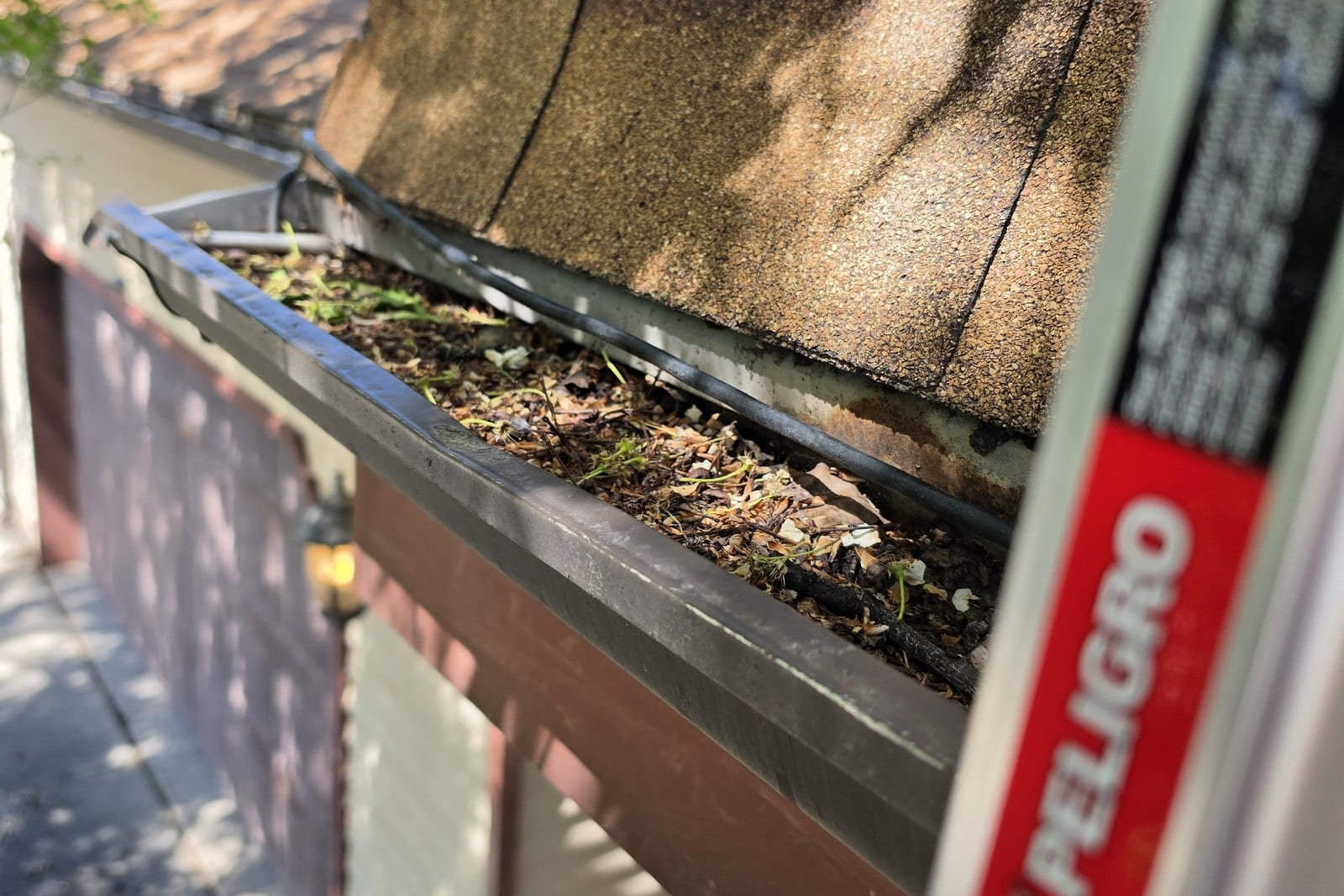 Clogged, debris-filled gutter in West Jordan, Utah before cleaning by Ember Window Cleaning