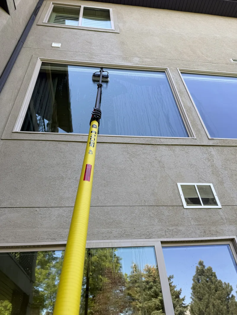 Residential window cleaning in Salt Lake City — Ember technician cleaning second-story windows with a water-fed pole