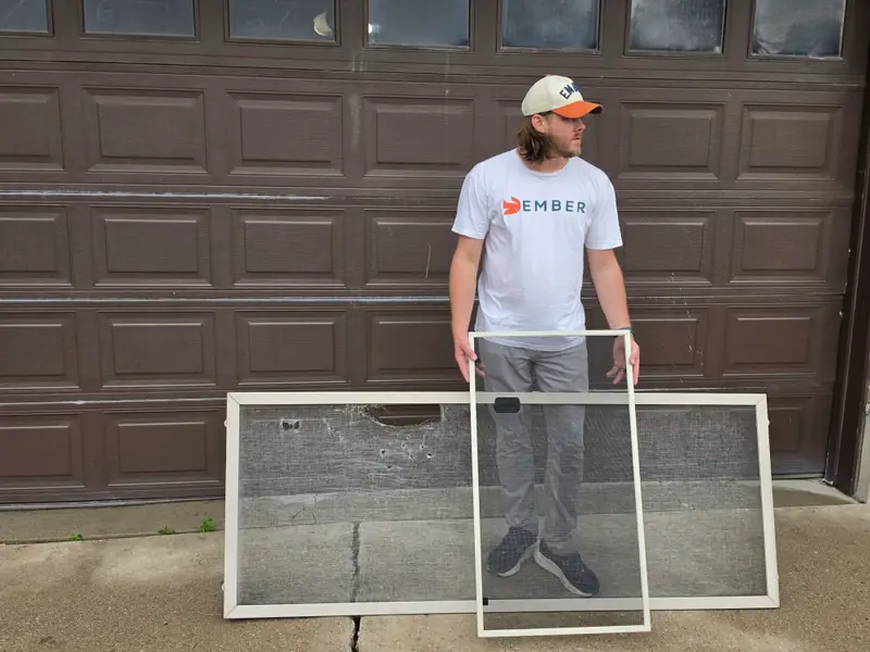 Screen repair in Salt Lake City — Ember technician holding a freshly rescreened frame in front of a torn window screen