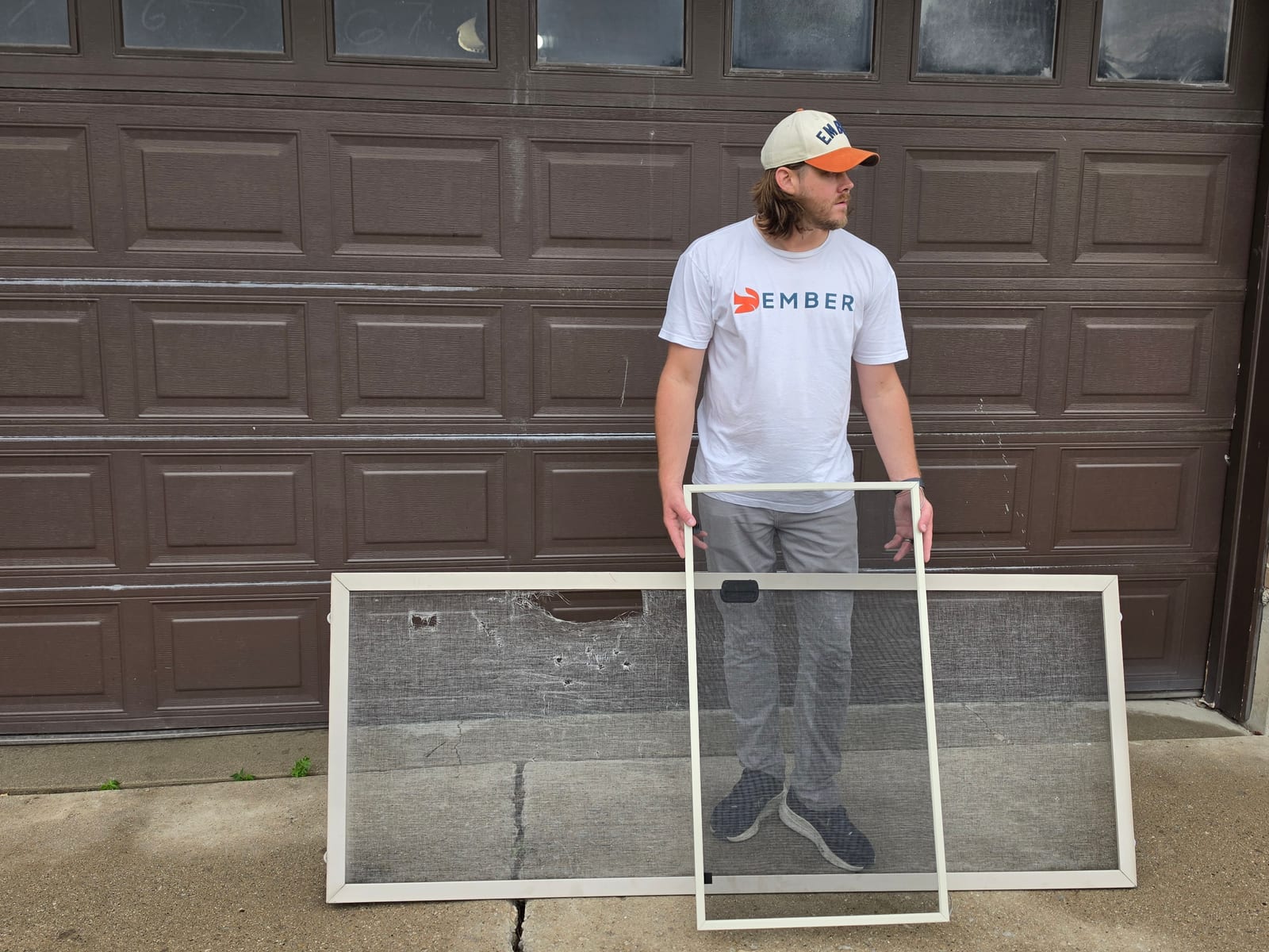 Screen repair in Salt Lake City — Ember technician holding a freshly rescreened frame in front of a torn window screen